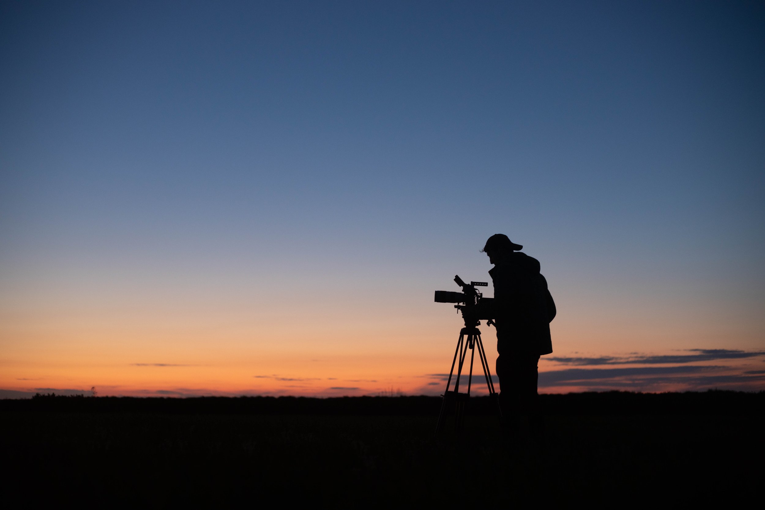 a photo of a camera operator in front of a  sunset.