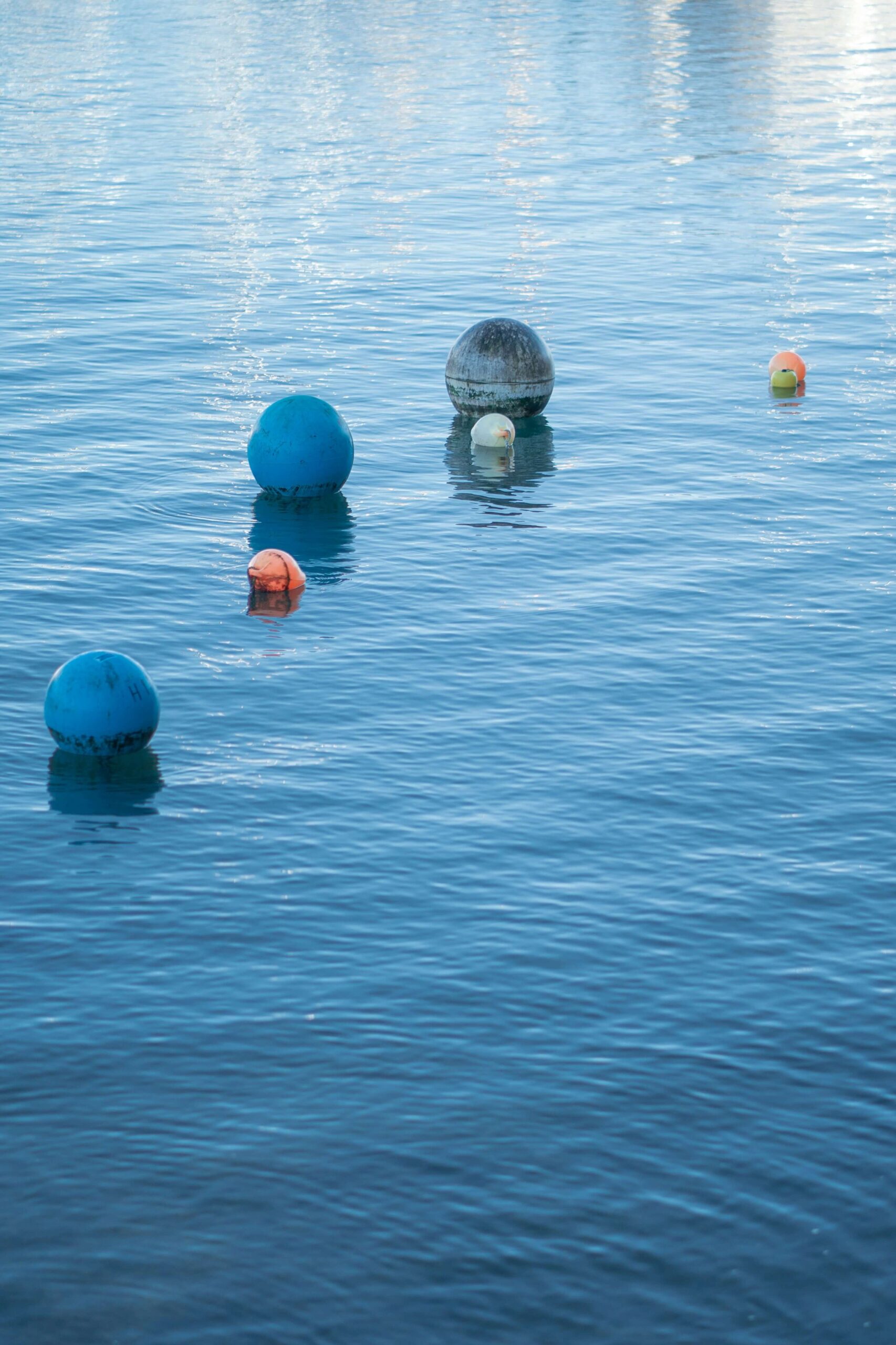 A picture of a glistening ocean with a number of buoys bobbing in the ocean.