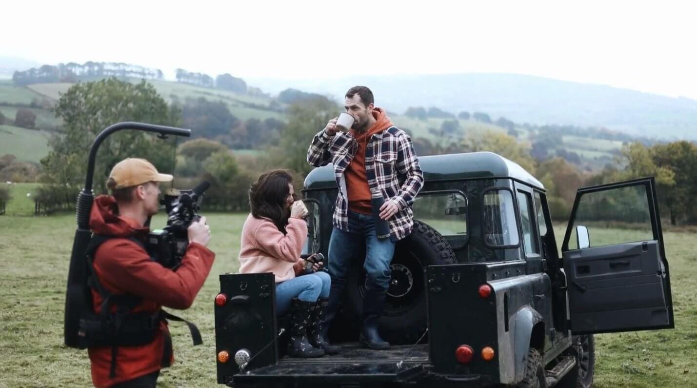 A Here Now Films camera operator filming FatFace models on the back of a Land Rover Defender.