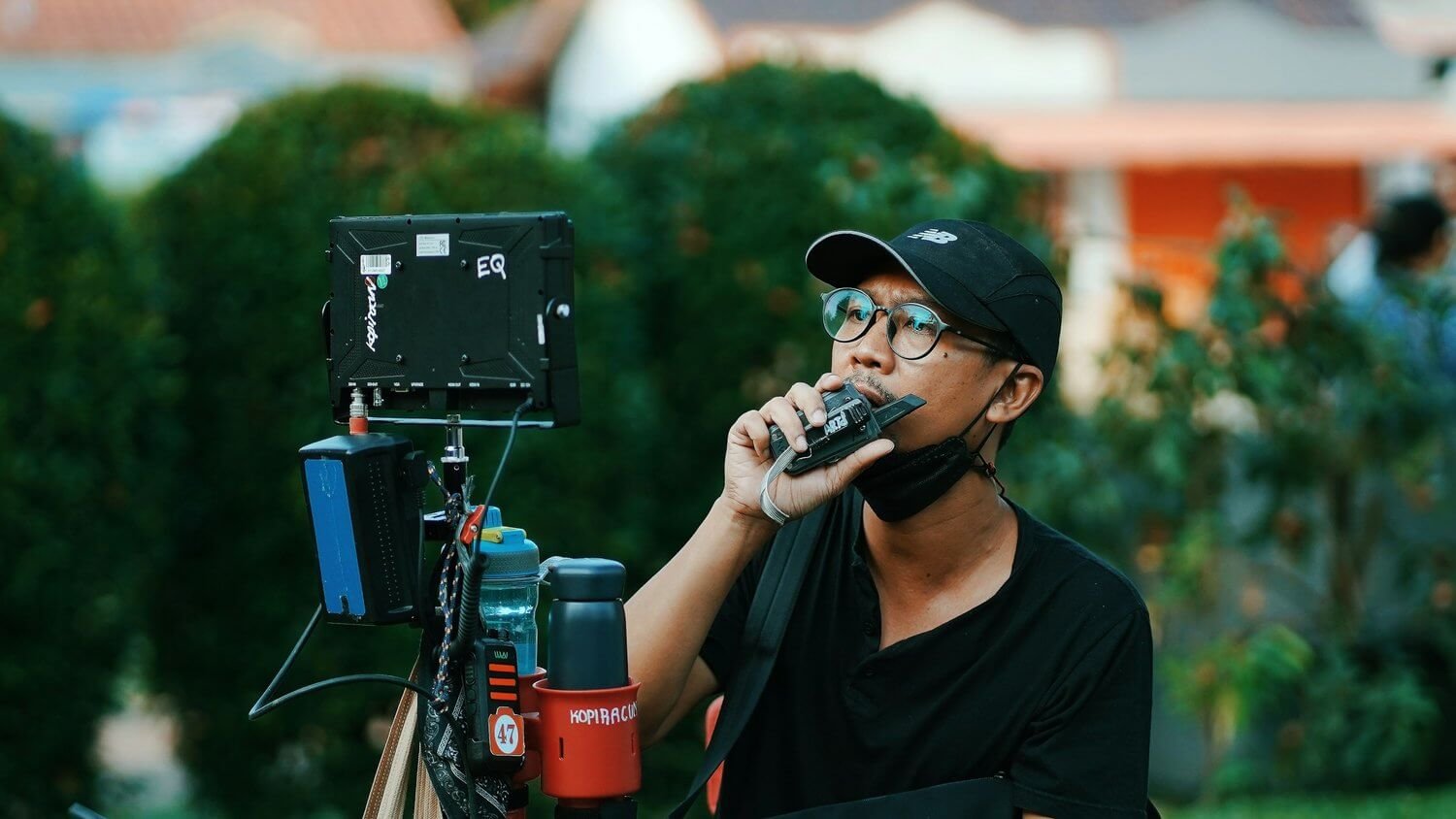 Header image for the film crew roles and responbsibilities blog. A producer holds a walkie talkie up to his mouth on set.