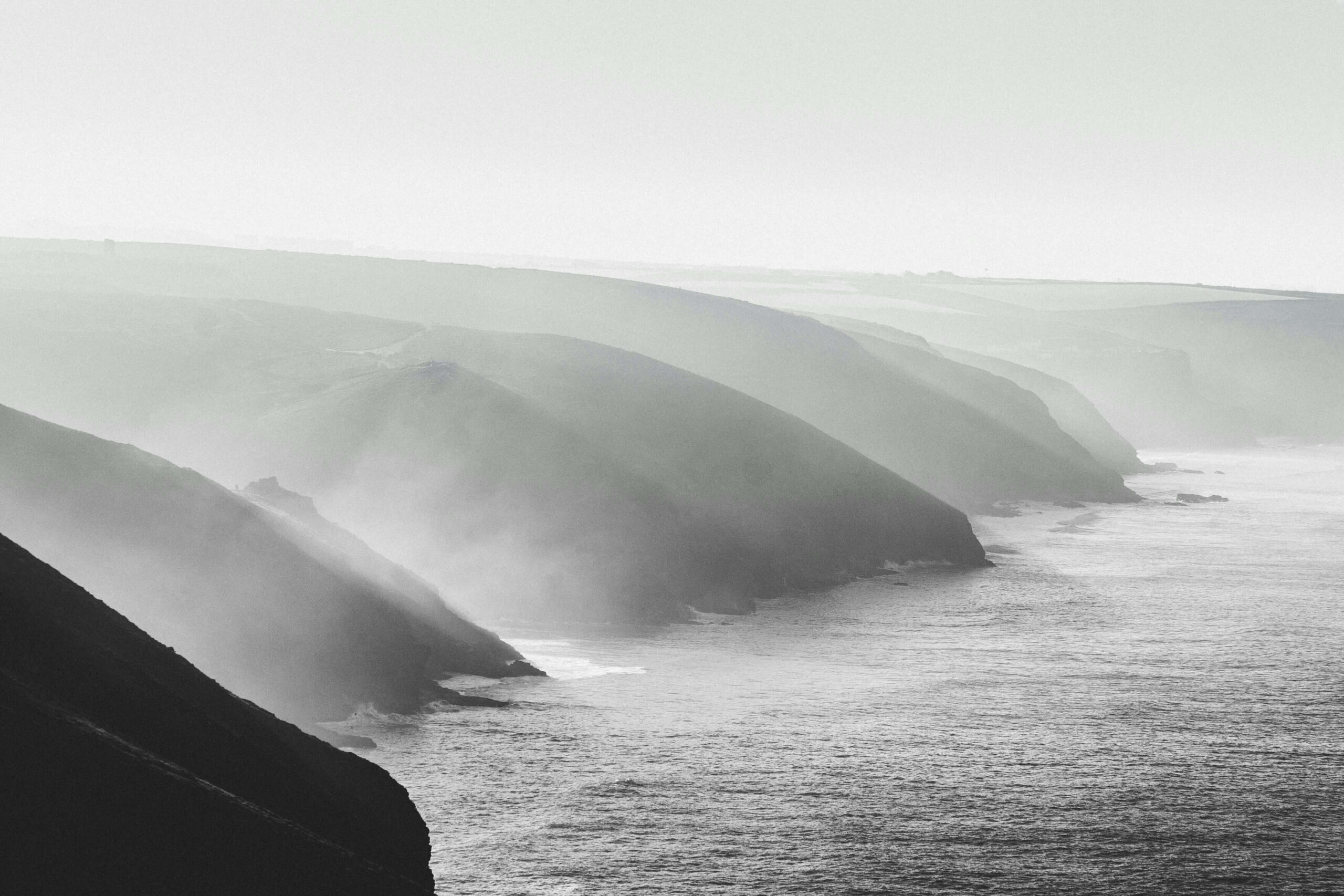 A black and white image of the North Coast of Cornwall with mist rising up from the sea.