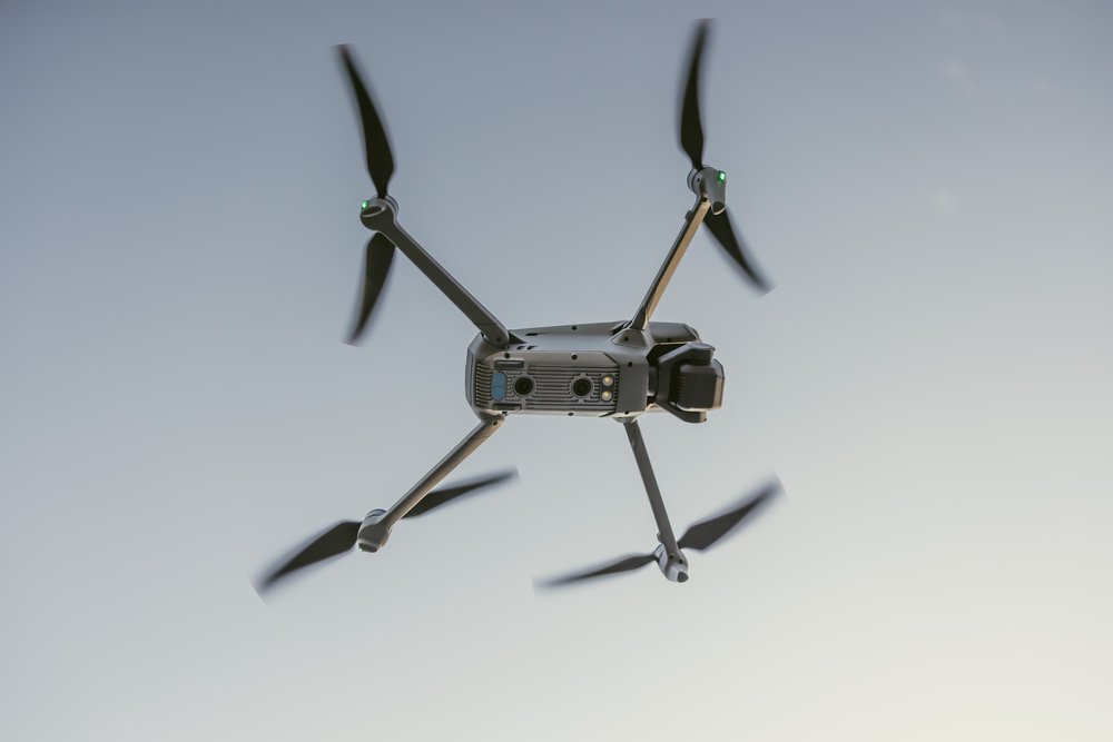 An image of a DJI Mavic cine pro flying above with a blue sky background.