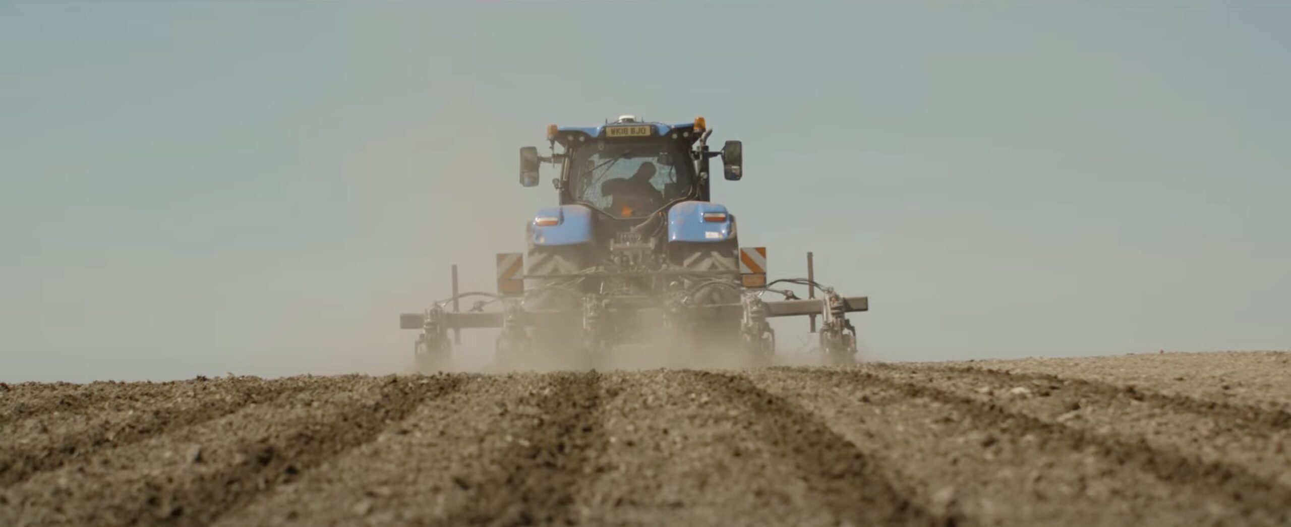 An image of a tractor in a field in Cornwall ploighing a field.