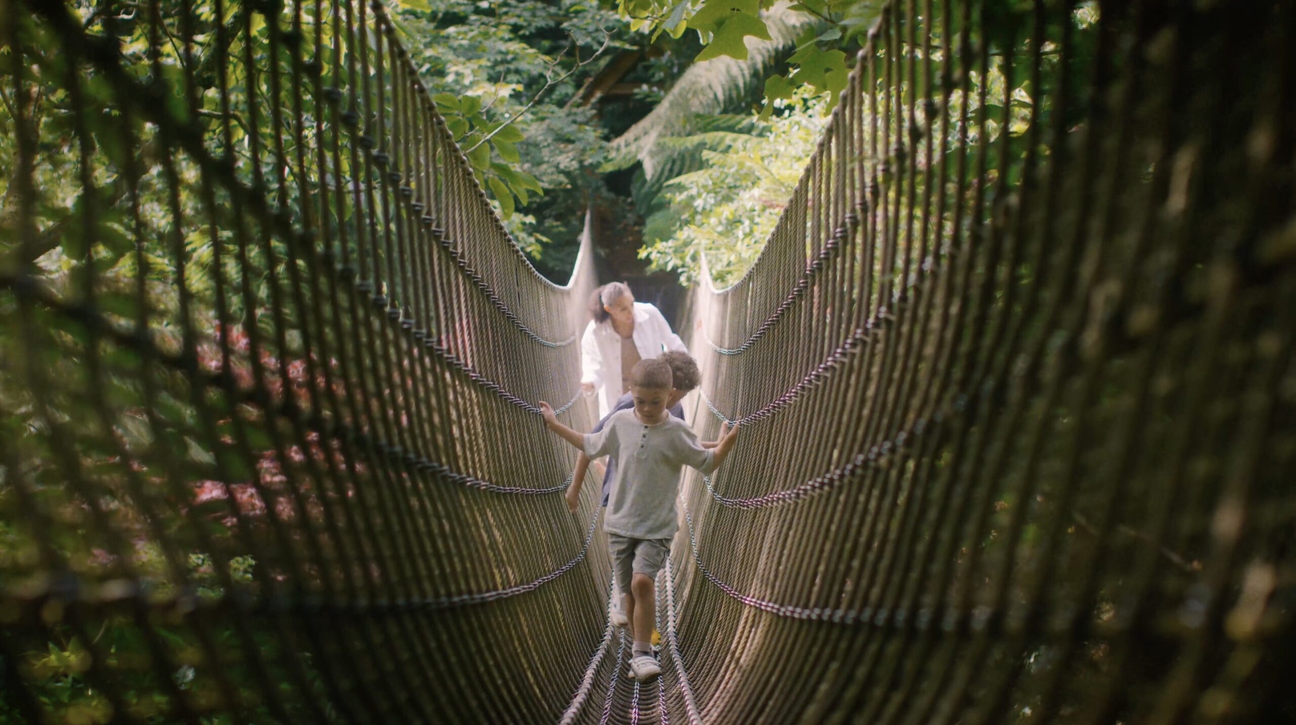 An image of a family crossing The Rope Bridge at Heligan Gardens.