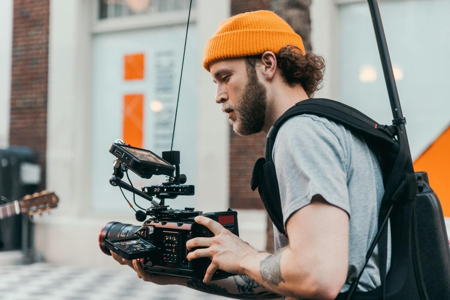 Side profile of a camera operator filming in the UK. He's wearing an orange hat.