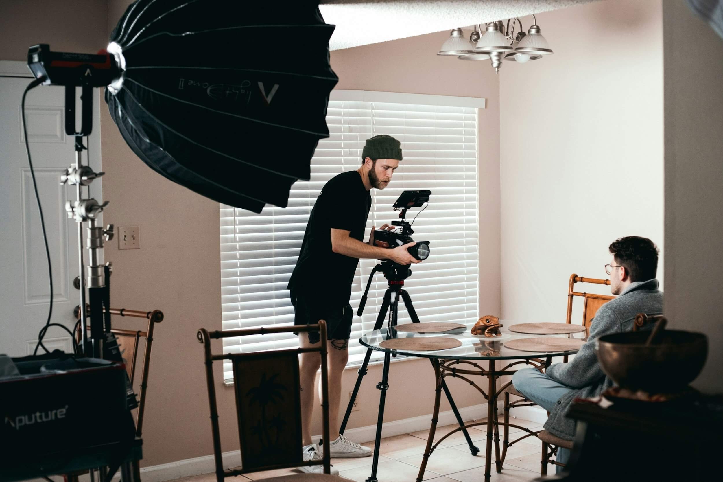 A videographer setting up an indoor interview. A film light is shining across the set.