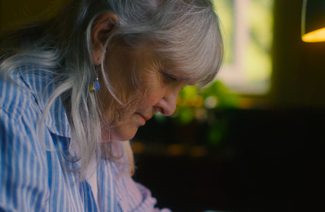 A colour graded image of an old lady painting in a shepherd hut.