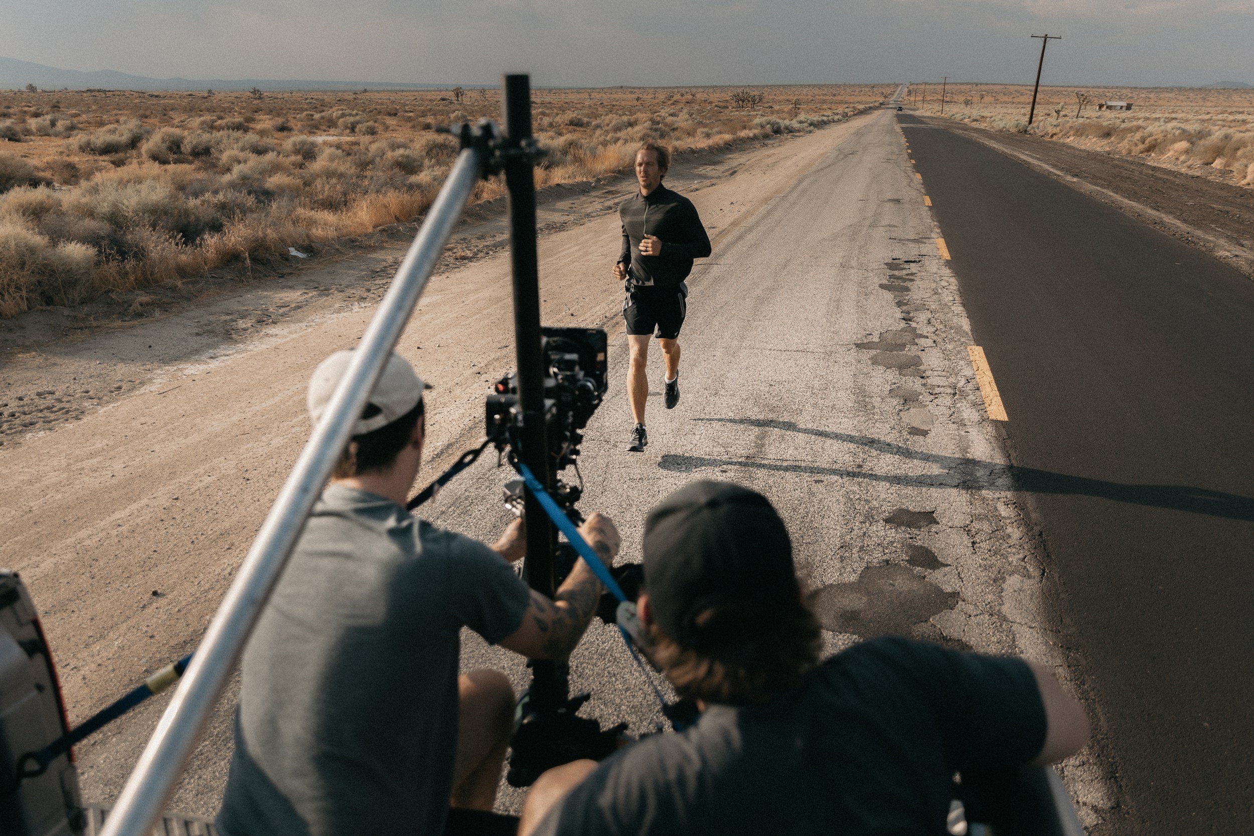 An executive producer on the back of a moving truck filming an athlete.