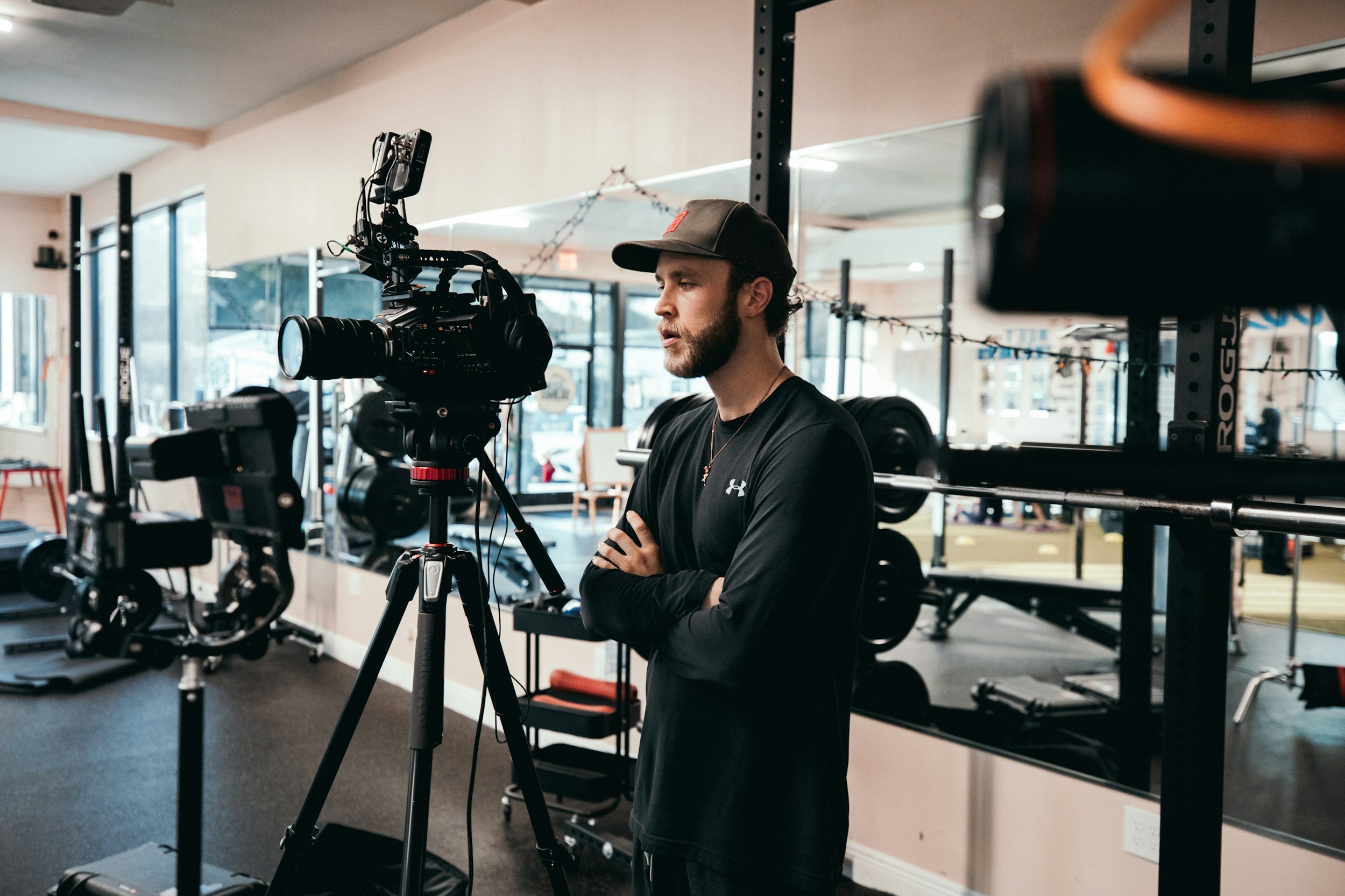 A male film director with his arms crossed, indoors, looking at a camera.