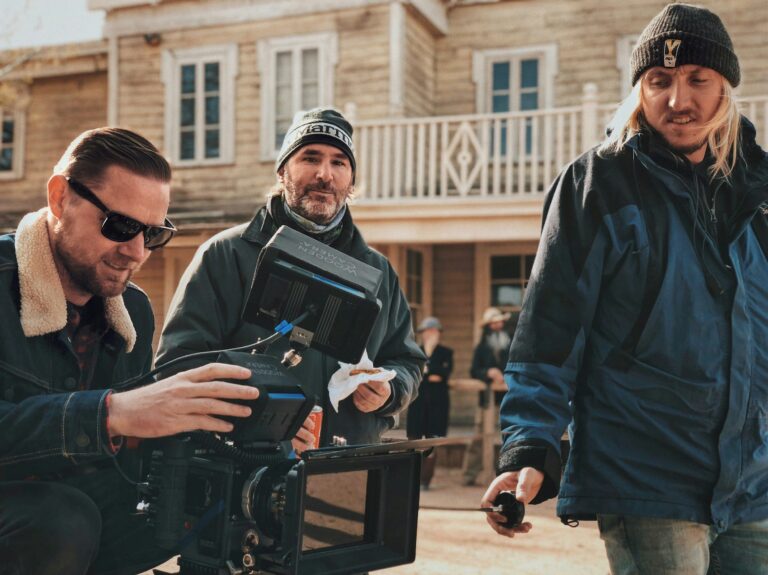 A film director looking into a screen monitor standing next to a director of photography.