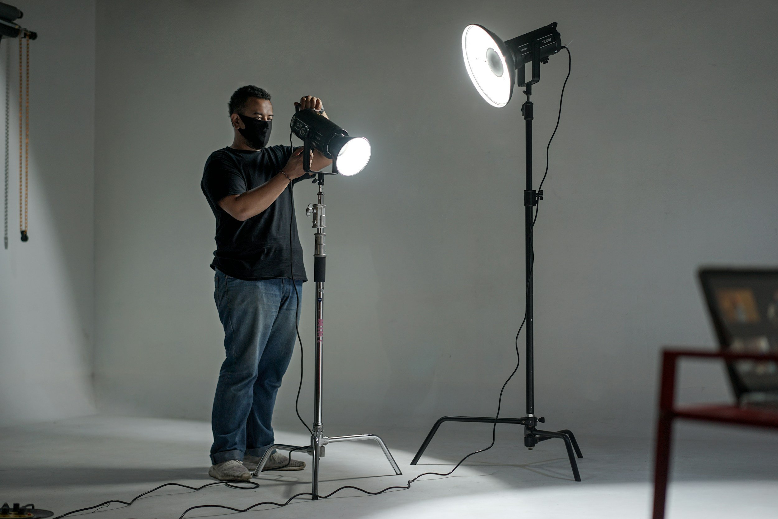 a picture of a male key grip setting up lighting indoors.