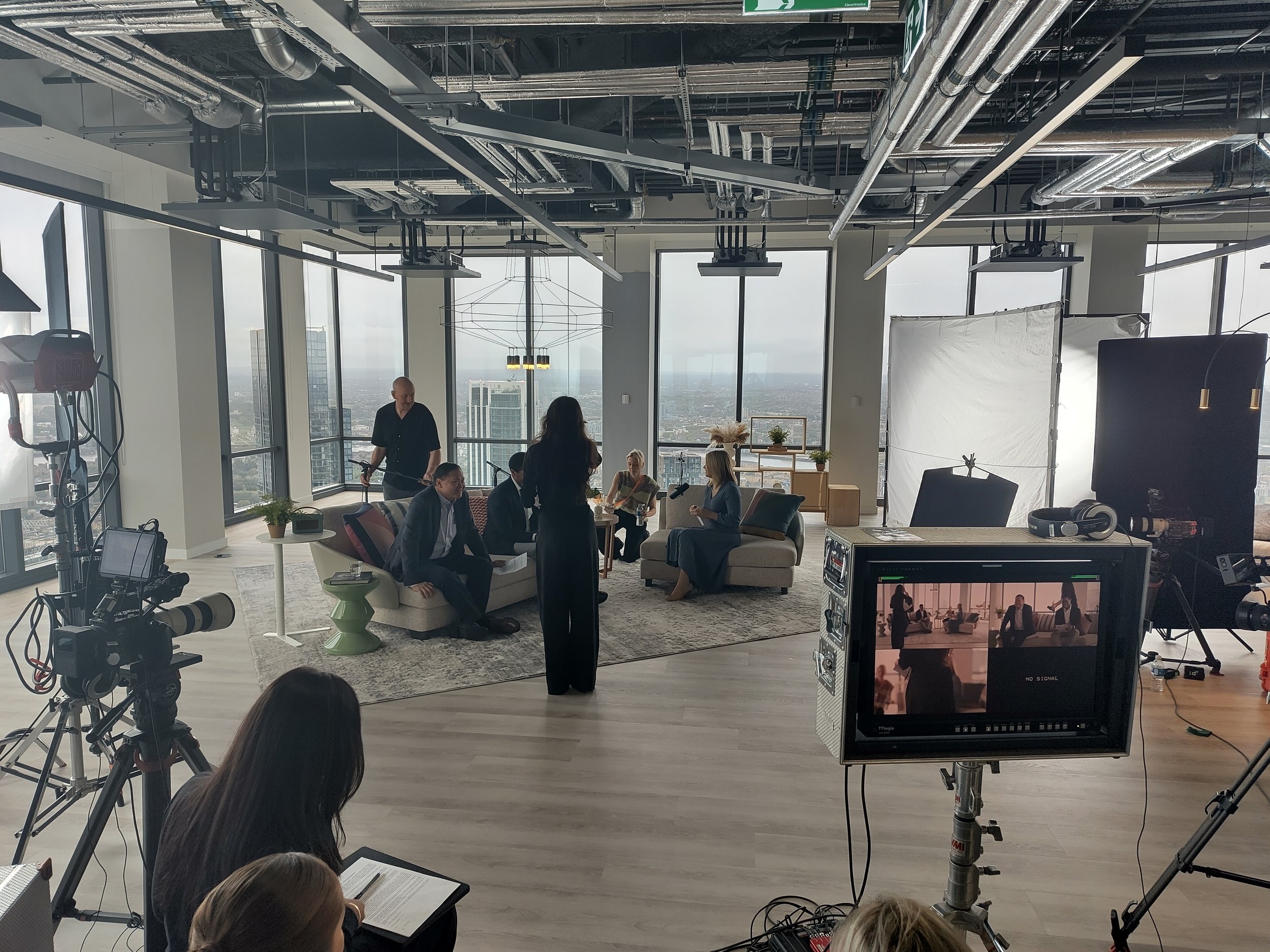 An image of a corporate film set, you see cameras, lighting and a view over London.