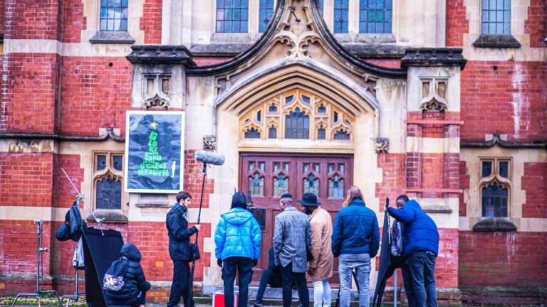 An image of a film crew in the UK standing outside of a red brick building in the United Kingdom.