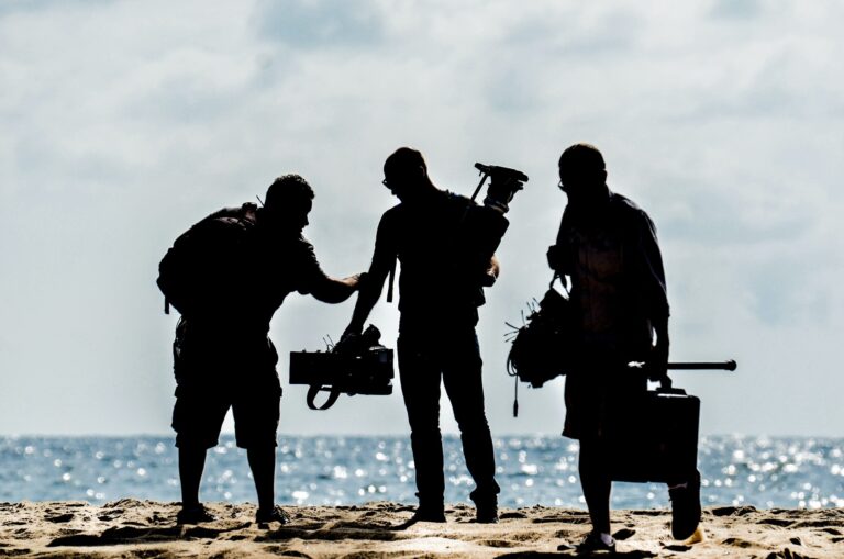 An image of an underwater videographer getting ready to film on the coast in Cornwall. His image is silhouette with two other people beside him.