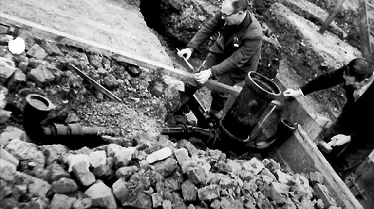 An old archival image of JA Brooks during the second world war fixing pipes.